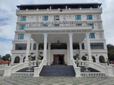 a large white building with stairs in front of it at Captains Crown Hotels & Resorts in Kushālnagar