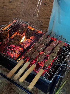 a grill with meat and wooden skewers on it at Rivulet Dale in North Paravur