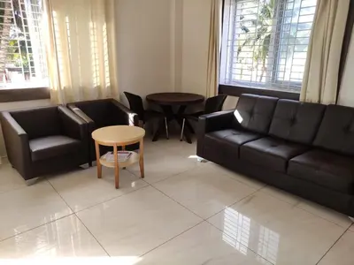 a living room with a black couch and chairs at Brindavan Service Apartments in Mysore