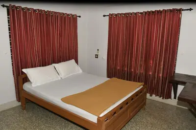 a bed in a room with red curtains at Pepper Nut Homestay in Thattakād
