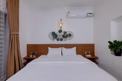 a bedroom with a large white bed with two tables at Bougainvillea Beach Home - Guruvayur - Chavakkad in Manattala