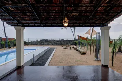 a view of a pool with tables and benches at Bougainvillea Beach Home - Guruvayur - Chavakkad in Manattala
