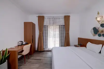 a bedroom with a bed and a desk and a window at Bougainvillea Beach Home - Guruvayur - Chavakkad in Manattala