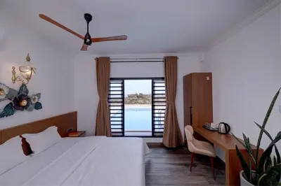 a bedroom with a bed and a desk and a window at Bougainvillea Beach Home - Guruvayur - Chavakkad in Manattala