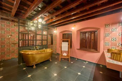 a bathroom with a copper tub and pink walls at Seclude Karthika Nivas, Thrissur in Trichūr
