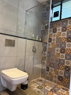 a bathroom with a toilet and a glass shower at Trumpet Deck 3BHK Container Home in Kutta