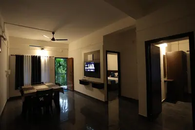 a living room with a table and a television at Emberlin Holidays in Wayanad