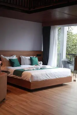 a bedroom with a large bed with a large window at Mercure Resort Wayanad in Mananthavady