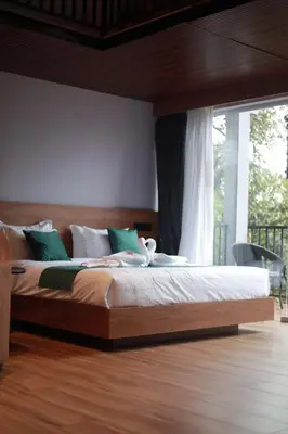 a bedroom with a large bed with green and white pillows at Mercure Resort Wayanad in Mananthavady