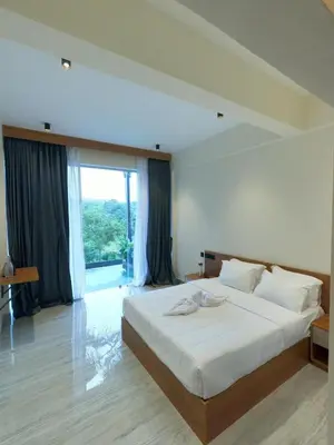 a bedroom with a large bed and a large window at Mercure Resort Wayanad in Mananthavady