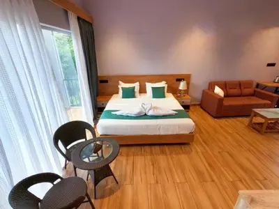 a bedroom with a bed and chairs and a couch at Mercure Resort Wayanad in Mananthavady