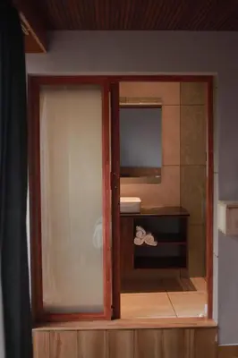a glass door to a bathroom with a mirror at Mercure Resort Wayanad in Mananthavady