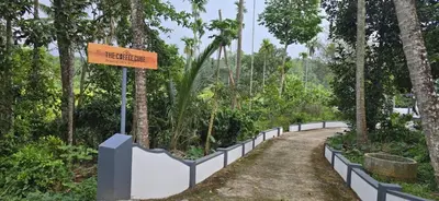 a sign in the middle of a dirt road with trees at The Coffee Cube in Kaniyāmbetta