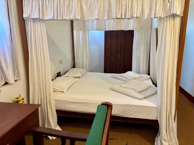 a bedroom with a bed with a curtain and a chair at FAMILY RESORT MARAYOoR KANTHALLOOR in Kanthalloor