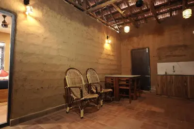 two chairs and a wooden table in a room at Papilio Mudhouse Stay in Edayūr