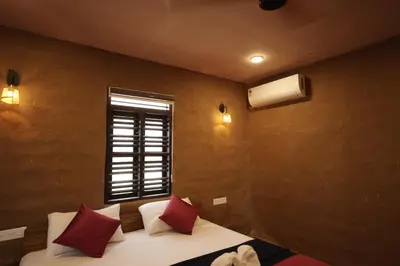 a bedroom with a bed with red pillows and a window at Papilio Mudhouse Stay in Edayūr