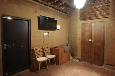 a room with two chairs and a tv on the wall at Papilio Mudhouse Stay in Edayūr