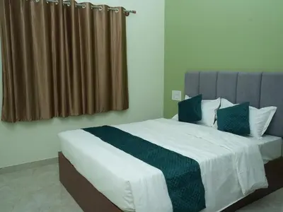 a bedroom with a large bed with green and white at Serene Legacy in Mysore