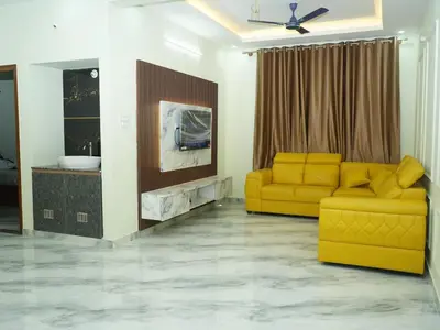a living room with a yellow couch and a tv at Serene Legacy in Mysore