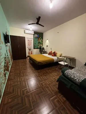 a bedroom with two beds and a wooden floor at Sihi-2 bhk Non AC and Penthouse AC Rooms in Mysore