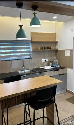 a kitchen with a wooden table and two lights at Vadanapilly Beach Villa for 8-10 adults in Irimbranallūr