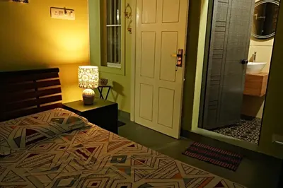 a bedroom with a bed and a door to a bathroom at Private 1BHK Kerala Village Homestay with Open Veranda near Thrissur in Cheruthuruthi