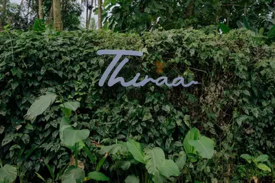 a sign on a hedge with plants at Thiraa Inn Nilambur By Hotelbuz in Nilambūr