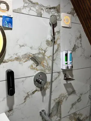 a shower in a bathroom with a marble wall at Heaven-Vadanapilly Beach Villa in Irimbranallūr