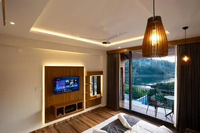 a living room with a tv and a large window at Lake Paradise Resort in Padinjarathara