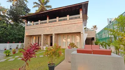 a house with two red chairs in a yard at Cherai Beach Regency in Ernakulam