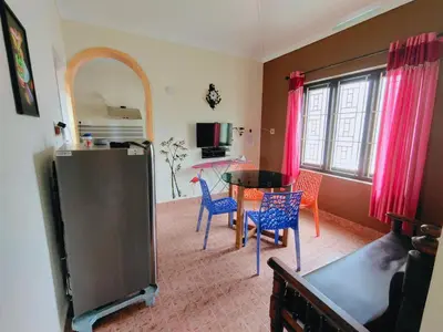 a living room with a table and chairs and a kitchen at 7th Heaven Kannur in Kannur