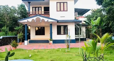 a large white house with a lawn in front of it at 7th Heaven Kannur in Kannur