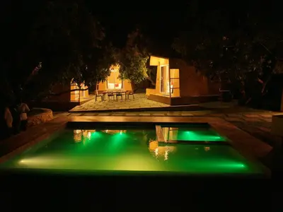 a pool with green lights in a yard at night at Bougainvillea HillView Retreat in Palakkad