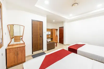 a hotel room with two beds and a mirror at Hotel faaz international in Thottada
