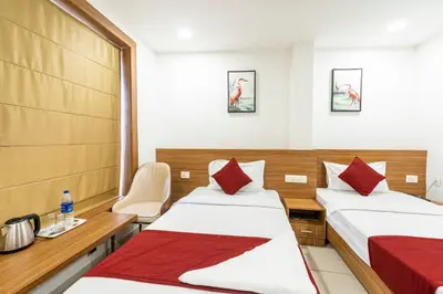 a room with two beds and a table and chairs at Hotel faaz international in Thottada