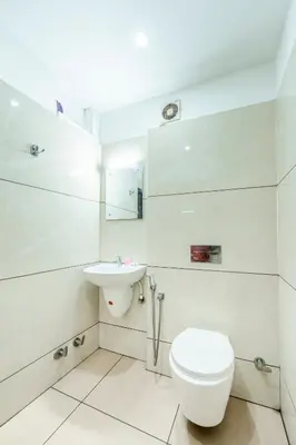 a white bathroom with a toilet and a sink at Hotel faaz international in Thottada