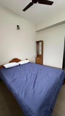 a bedroom with a blue bed with a ceiling fan at Chandras appartment in Palakkad