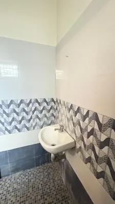 a bathroom with a sink and a tiled wall at Chandras appartment in Palakkad