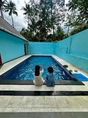two girls are sitting next to a swimming pool at Cloud Lacasa in Athirappilly