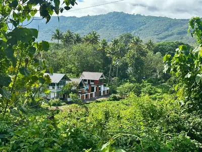 a house in the middle of a forest with mountains in the background at Cloud Lacasa in Athirappilly
