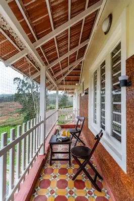 a screened porch with two chairs and a table at Mihirika's Nirvana 5-BHK With Garden, Gazebo, Bonfire Pit & Scenic Views in Ooty