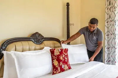 a man is putting pillows on a bed at Mihirika's Nirvana 5-BHK With Garden, Gazebo, Bonfire Pit & Scenic Views in Ooty