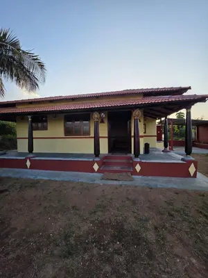 a small house with a palm tree in front of it at Namma Hatti, Traditional Home in Chattanahalli