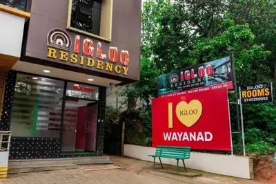 a sign for a restaurant with a bench in front of a building at Igloo Residency in Vythiri