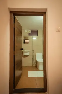 a bathroom with a toilet and a sink and a door at Cozy Nest Villa in Mananthavady