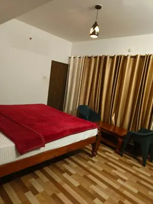 a bedroom with a bed and a desk and curtains at Tea Garden stays in Ooty