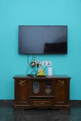 a flat screen tv on top of a wooden cabinet at 2Bhk White House Near Isha By Shivalaya Stays in Coimbatore