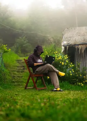 a man sitting in a chair with a laptop at Elim Retreat kanthalloor in Kanthalloor