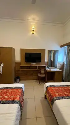 a hotel room with two beds and a flat screen tv at Sonam hotel and restaurant in Kushālnagar