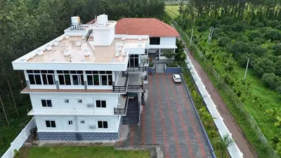 a white house with a car parked in front of it at Sonam hotel and restaurant in Kushālnagar